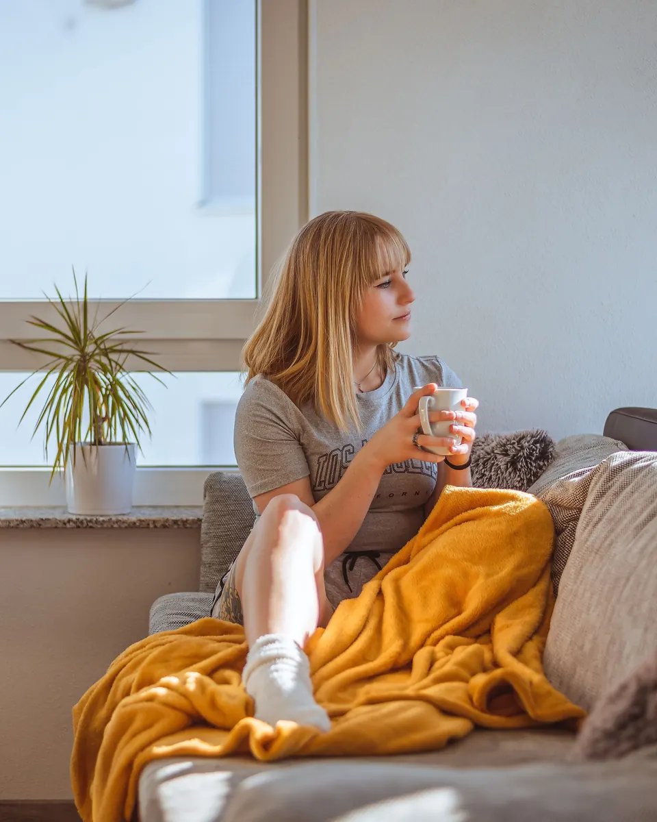 Someone relaxing at home on the sofa with a cup of coffee